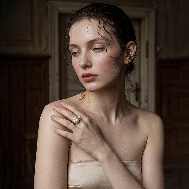 woman wearing Loxun asymmetrical pearl ring on finger baroque and round pearl gold stacked with other rings