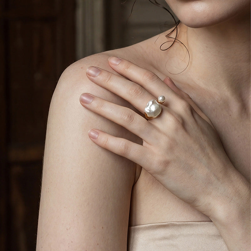 woman wearing Loxun asymmetrical pearl ring on finger baroque and round pearl gold stacked with other rings